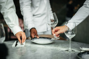 Medewerkers van Served With Passion dekken samen een tafel — een beeld van samenwerking, respect en inclusieve werkcultuur binnen de hospitality. Diversiteit, gelijkwaardigheid en teamwork vormen de kern van hun werkomgeving.