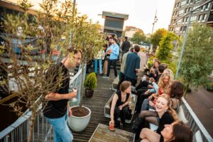 Groep mensen geniet van een borrel tijdens zonsondergang op een dakterras bij SquashCity.