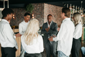 Trainer van Served With Passion motiveert een team van hospitalitymedewerkers tijdens een briefing volgens de 1-op-7 formule, waarbij één Eerste Medewerker zes teamleden begeleidt om kwaliteit, rust en gastvrijheid op de werkvloer te waarborgen.