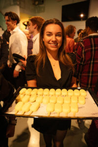 Vrouw houdt een dienblad met gele SWP-180 ijsjes vast op een drukbezocht evenement.