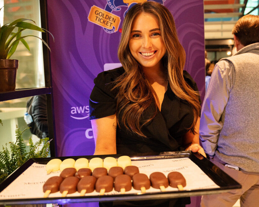 Hostess van Served With Passion verwelkomt gasten tijdens het exclusieve Upside Down Amsterdam event met een Magnum Golden Ticket-thema. Ze presenteert luxe ijsjes tijdens de champagneontvangst – een voorbeeld van hoogwaardige hospitality, gastvrijheid en beleving tijdens een volledige event buy-out