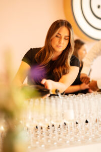 Vrouw schenkt mousserende wijn in champagneglazen tijdens een evenement.