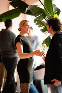 Twee mensen in gesprek met een glas champagne tijdens een sociaal evenement bij SWP-54.