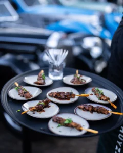 Ronde dienblad met smakelijke satéspiesjes op kleine bordjes, geserveerd tijdens The Perridon Collection event bij Wheels Marienwaerdt.