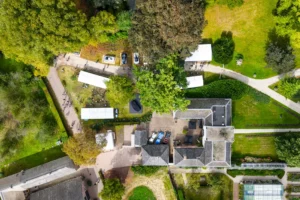 Luchtfoto van het evenement Wheels Marienwaerdt met tenten, auto's en bezoekers te midden van bomen en gebouwen.