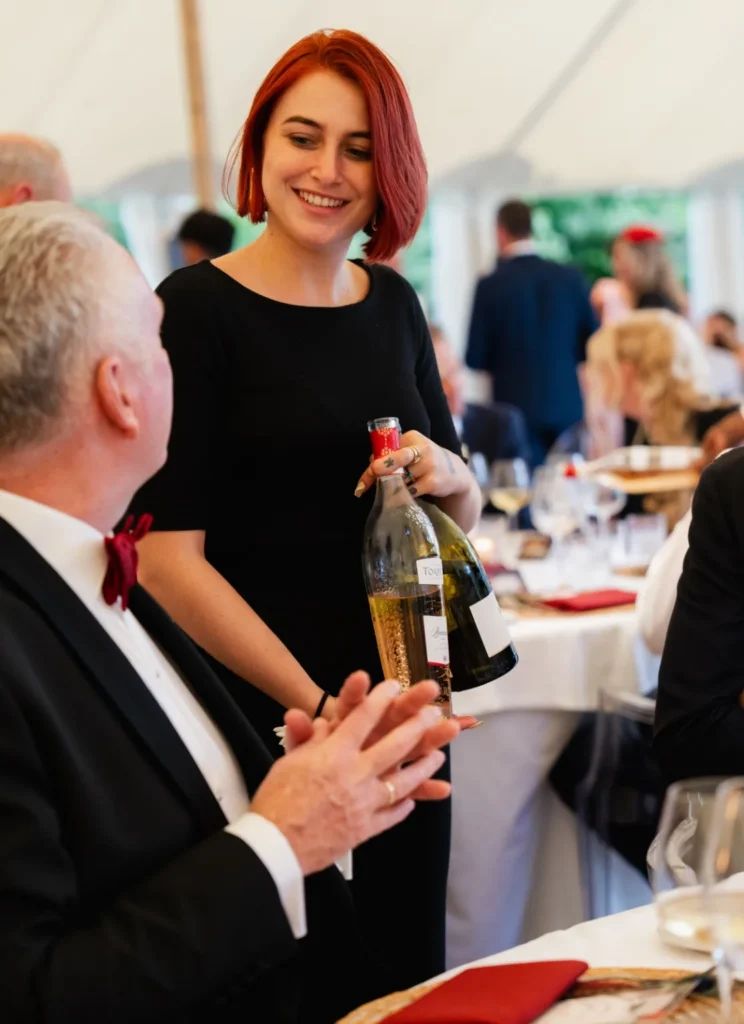 Eva Bouwman serveert wijn met een glimlach tijdens een chic diner.