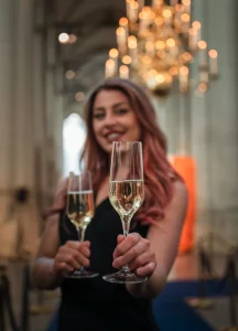 Hostess met twee glazen champagne in een chique, sfeervol verlichte ontvangsthal.