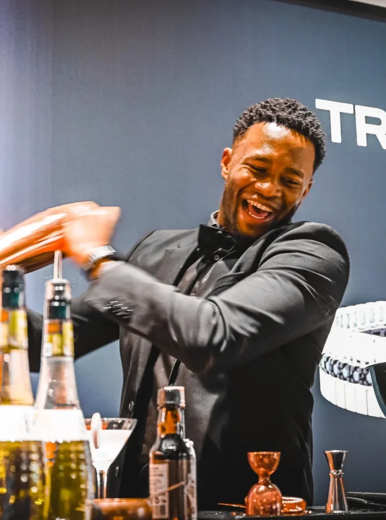 Barman in smoking maakt een cocktail met een shaker tijdens een evenement.