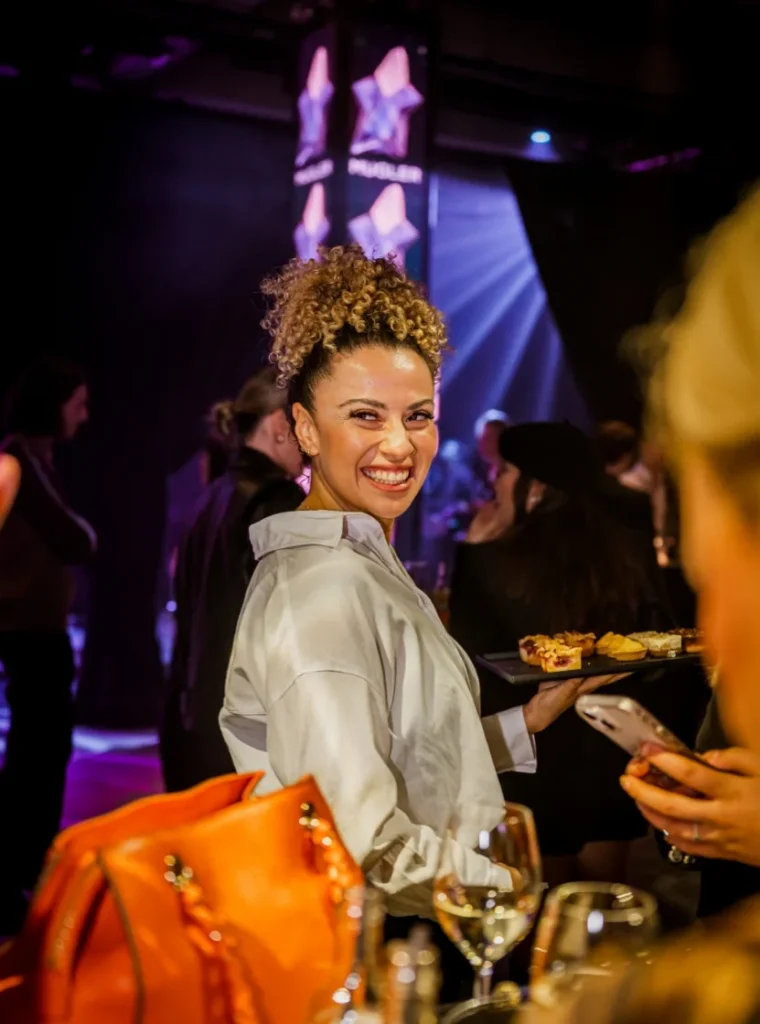 Vrolijke serveerster met een schaal hapjes tijdens een feestelijk evenement.