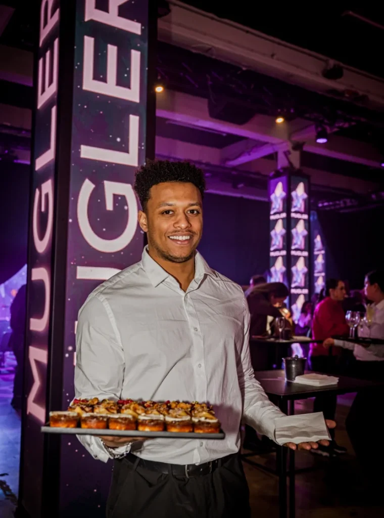 Ober met een dienblad vol gebakjes tijdens het Mugler-evenement.