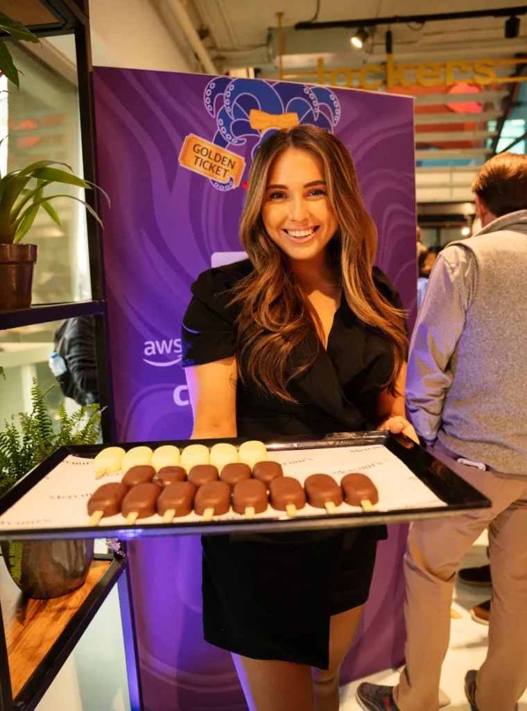 Hostess met lange bruine haren presenteert een dienblad met mini-ijsjes tijdens een evenement.