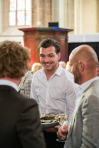 Man in witte blouse serveert een schaal met oesters tijdens een chique netwerkevenement.