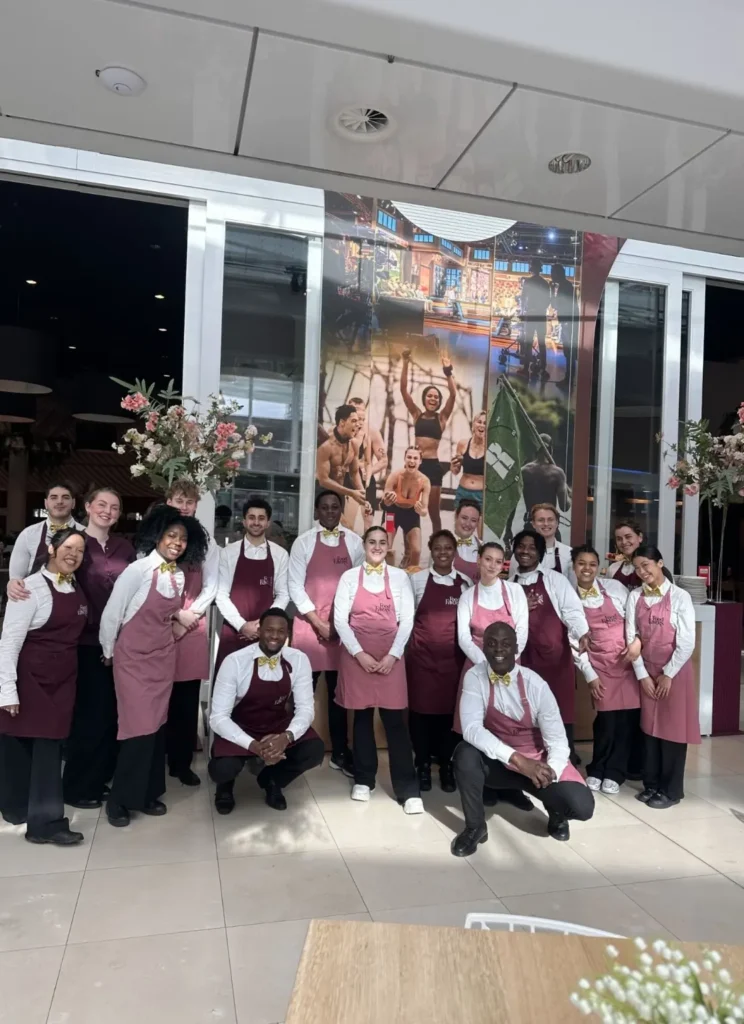 Groepsfoto van het team van Foodfavors in uniform, poserend voor hun locatie.